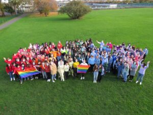 A rainbow flag of students and staff on the final day of Stand Up Week.